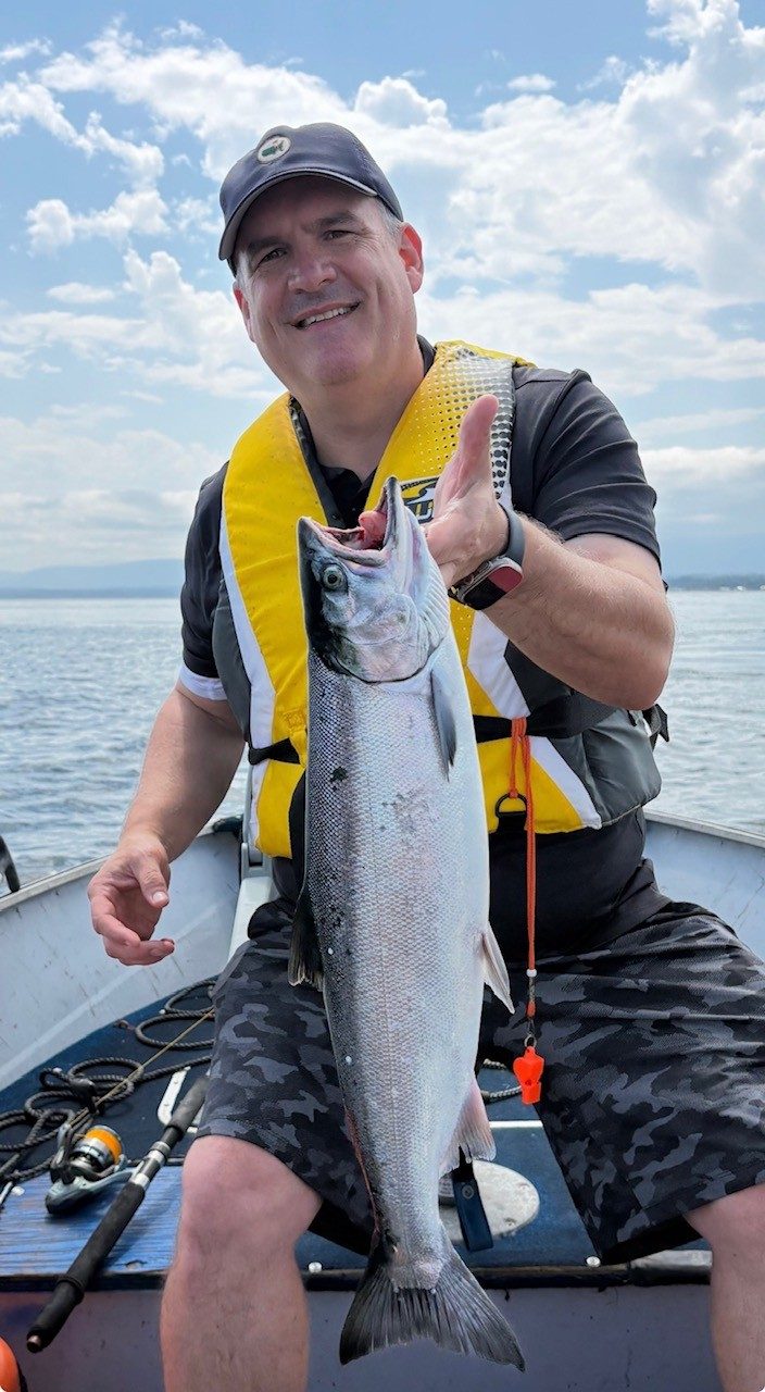 Thomas Corbett holding a coho salmon on a boat off the west coast